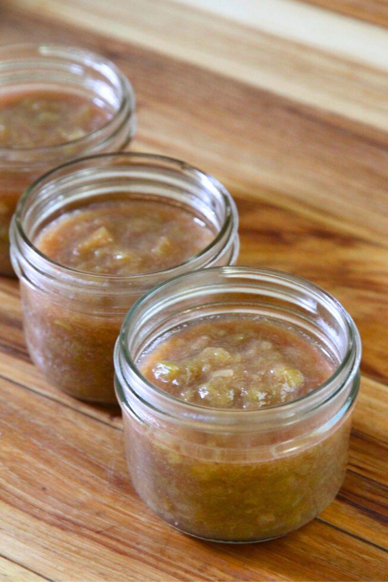 Jars of rhubarb jam cooling on the kitchen countertop without lids.