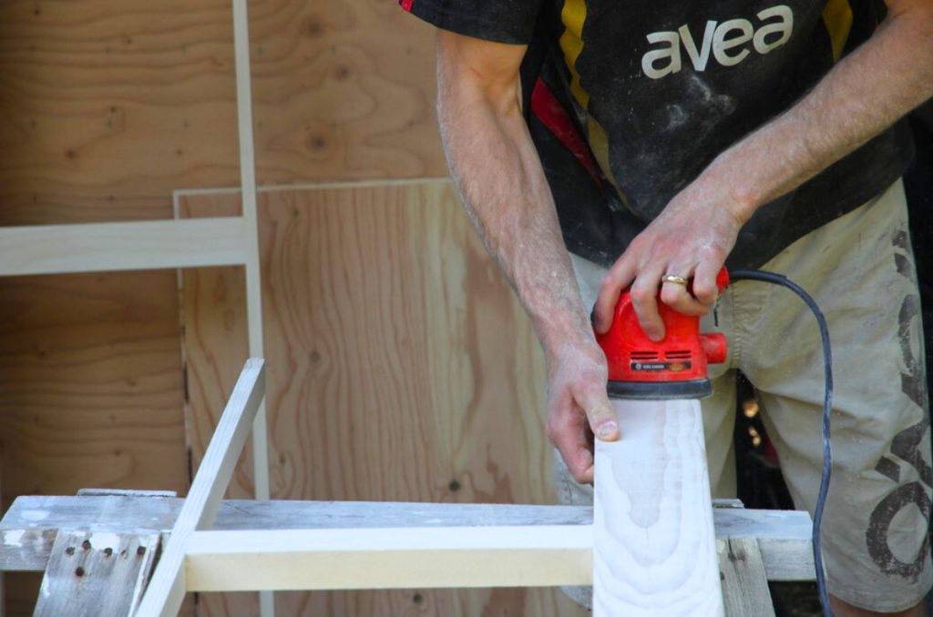Sanding the side of a wooden bed panel prior to painting