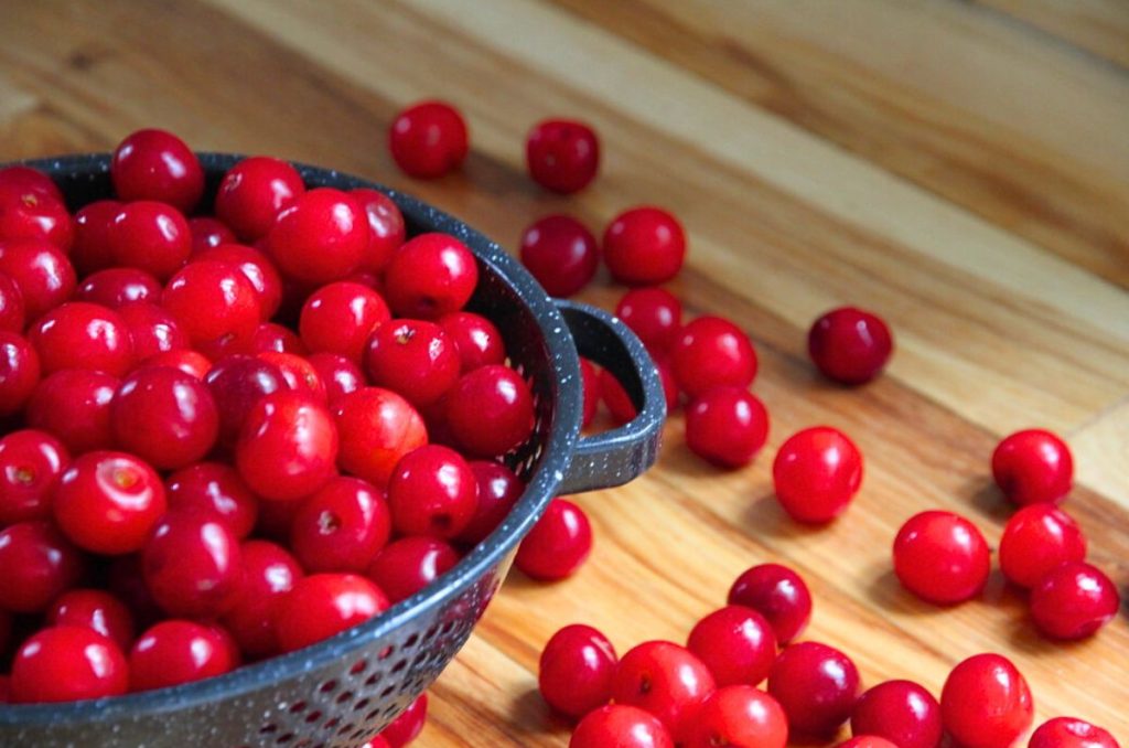 An enamel colander filled with fresh sour pie cherries