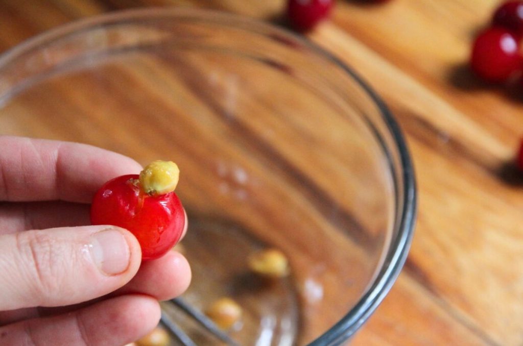 A sour cherry with a bright yellow seed sitting on top of the fruit.