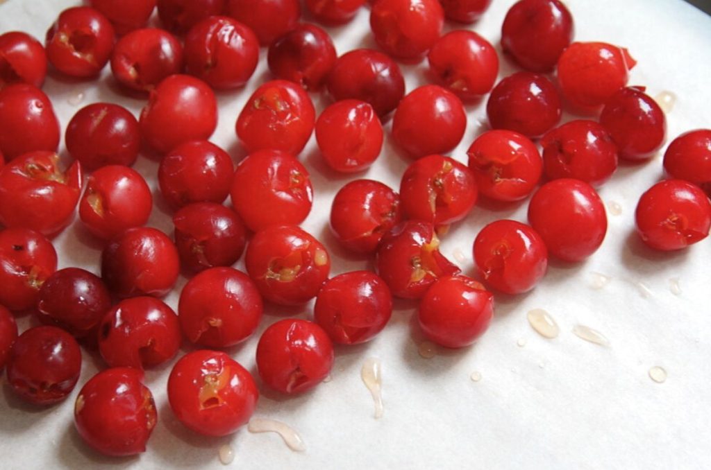 Pitted sour cherries on a baking sheet lined with parchment paper.