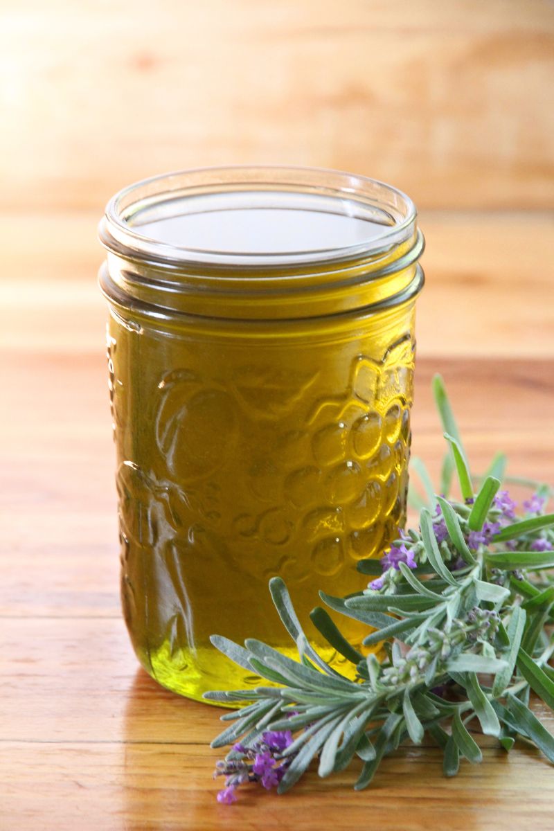 A jar of avocado infused lavender oil, with a fresh bundle of lavender beside.