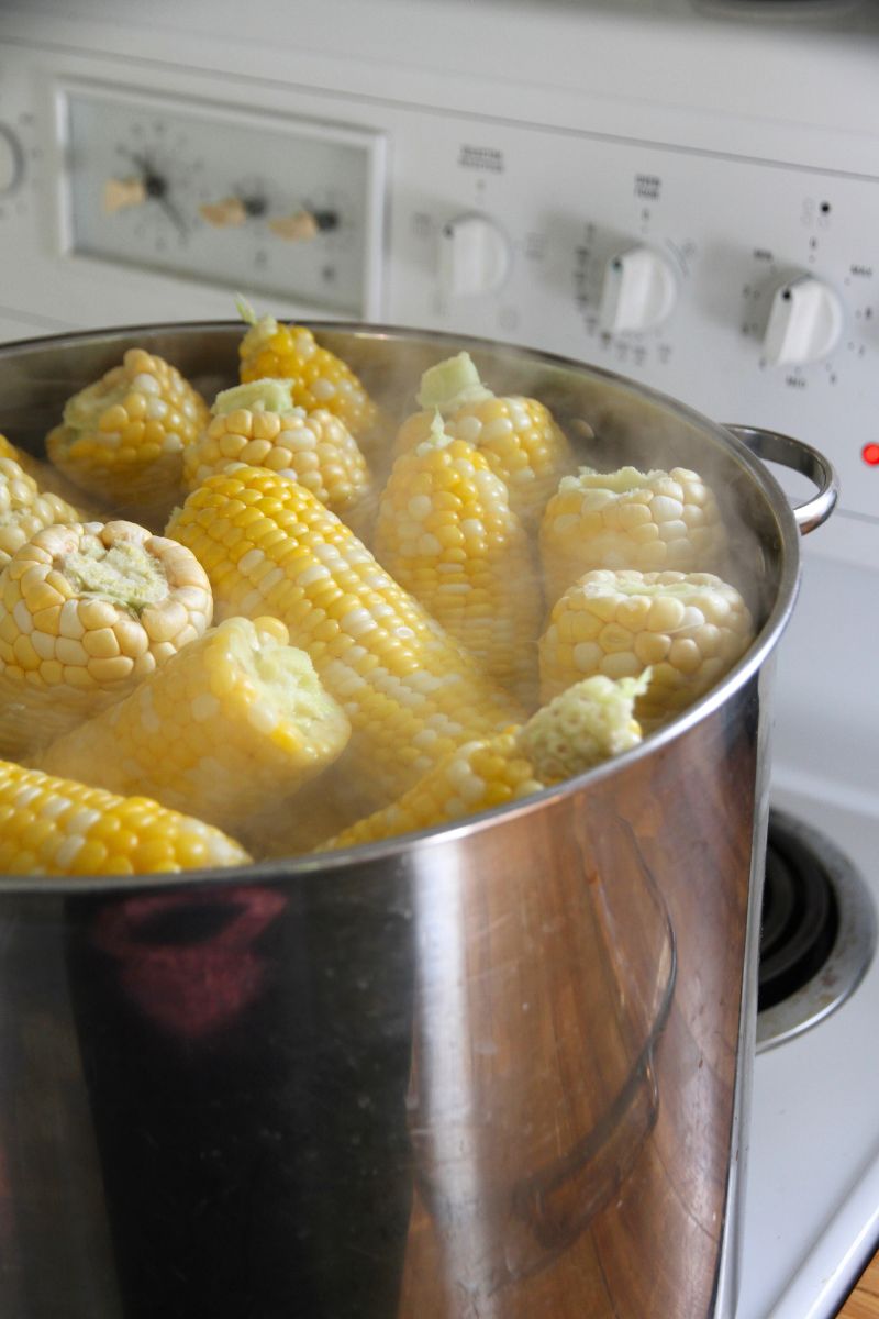 A large pot filled with hot water and sweet corn.