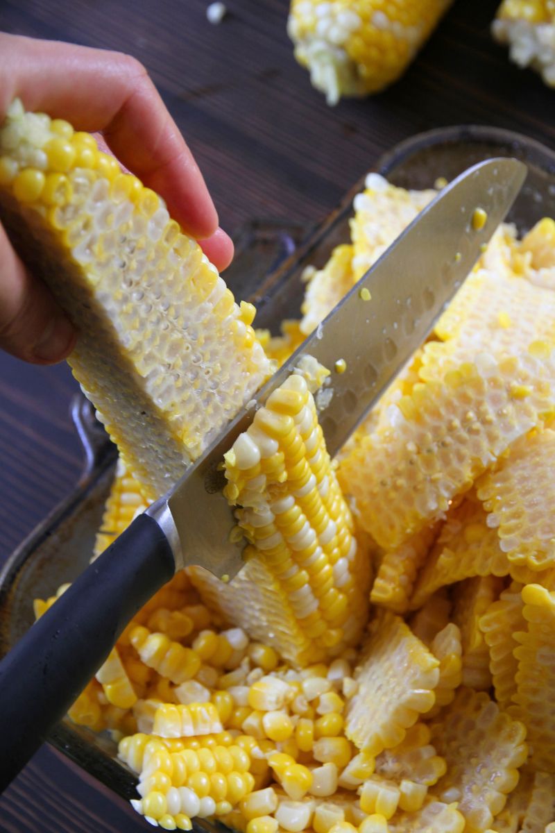 Slicing slabs of milky corn from the cob with a sharp kitchen knife