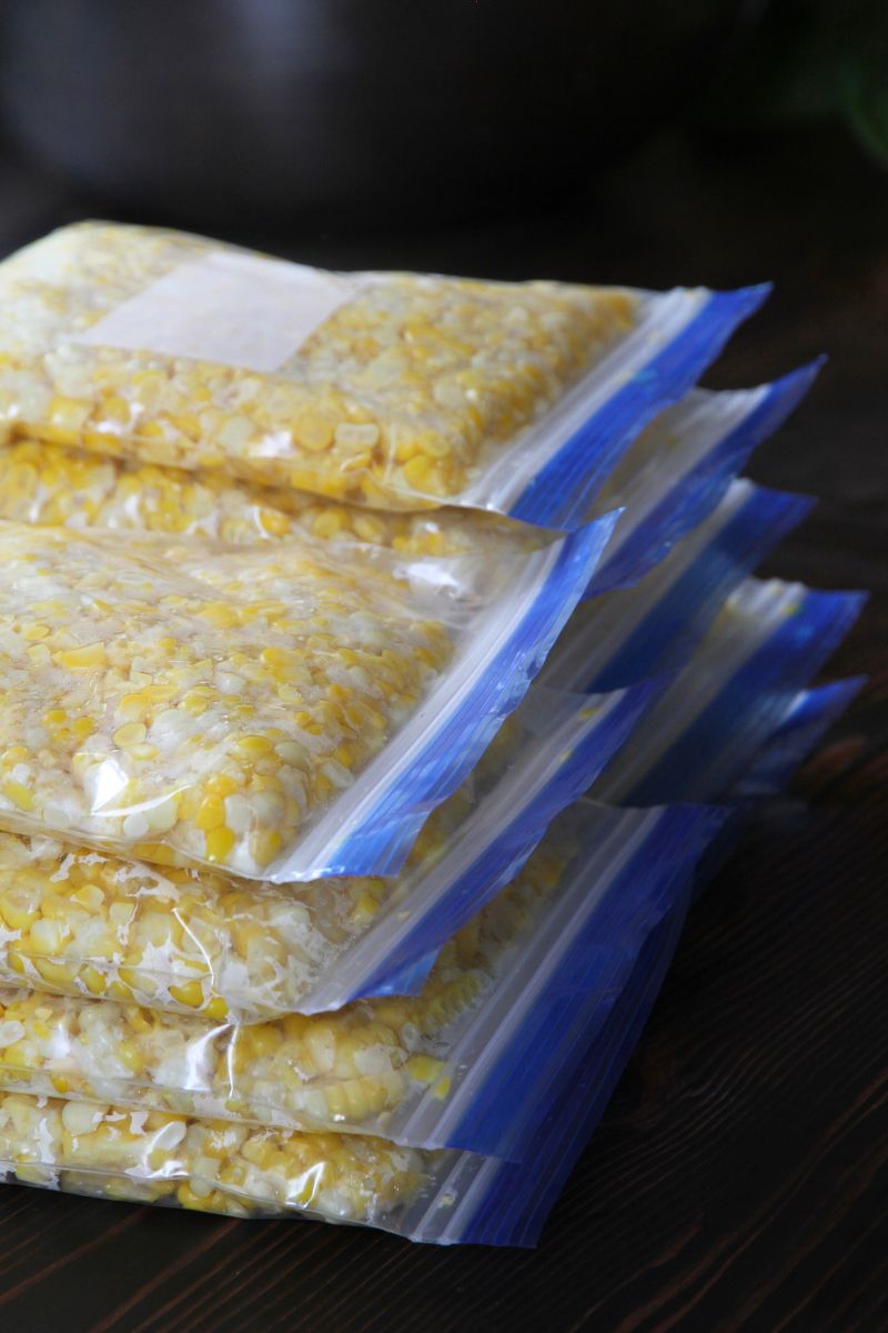 8 stacked plastic bags filled with sweet corn, ready to be put into the freezer.