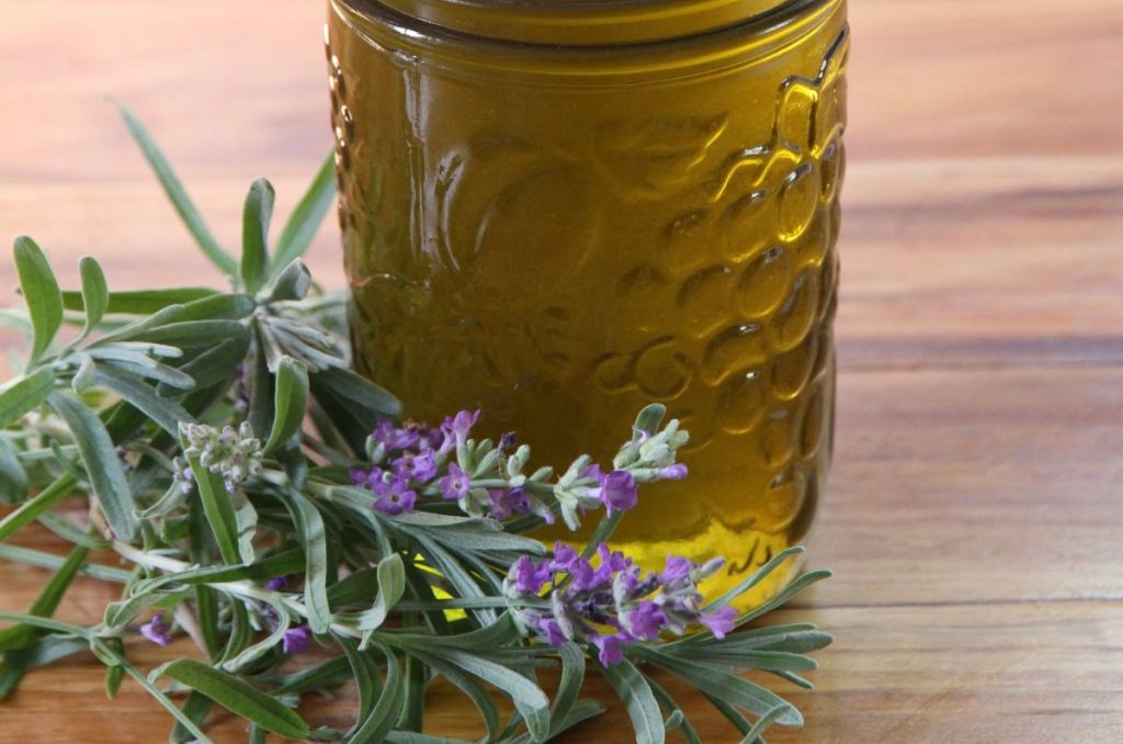 Fresh lavender adorning the base of a jar of lavender infused oil.
