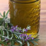 Fresh lavender adorning the base of a jar of lavender infused oil.