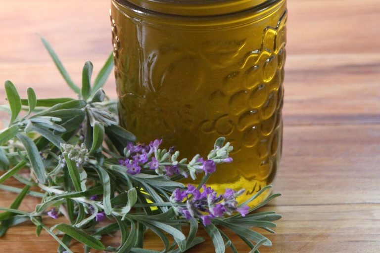 Fresh lavender adorning the base of a jar of lavender infused oil.