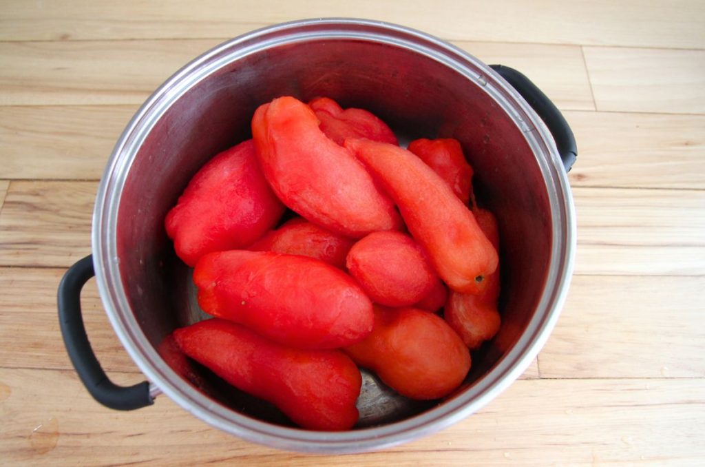 A large pot filled with whole frozen peeled tomatoes.