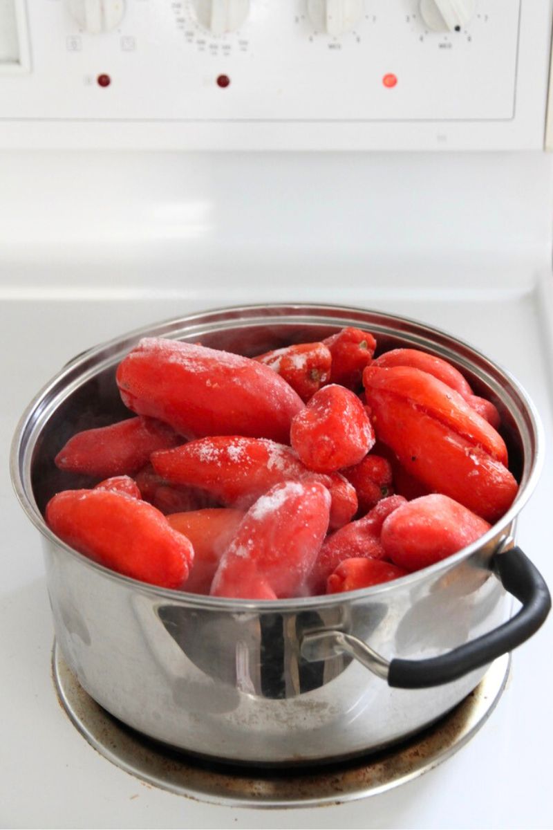 A pot filled with whole frozen tomatoes, ready to be cooked down.