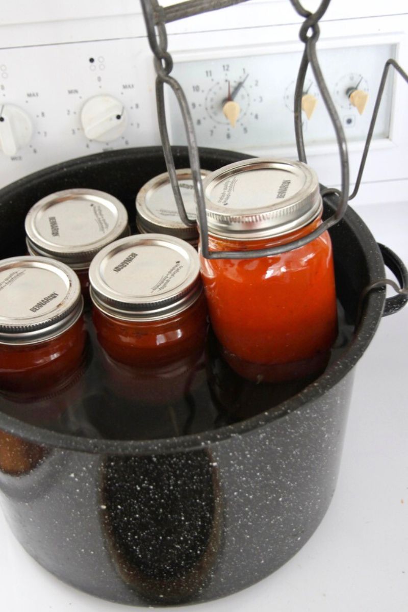 Loading canning jars into the water bath canner with a jar lifter.