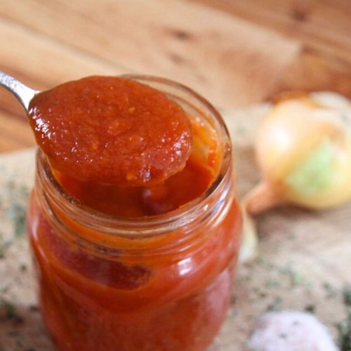 An opened jar of thick tomato sauce, ready for use in the kitchen.