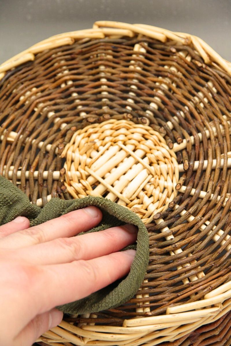 Wiping a freshly cleaned basket with a damp rag to remove extra moisture. 