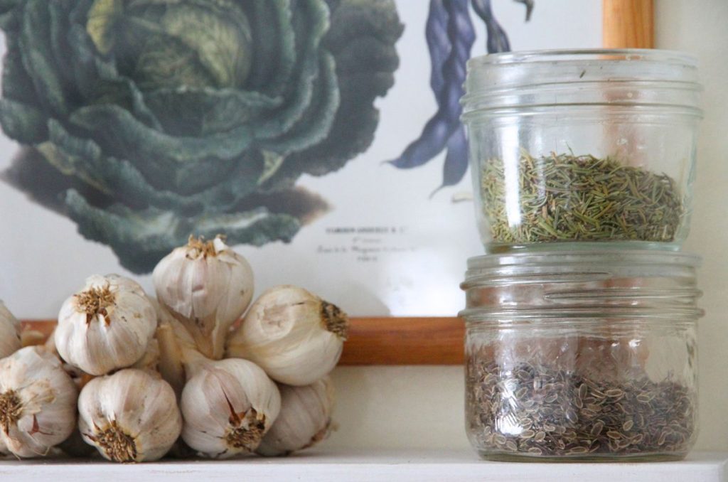Two 250 ml glass jars with glass lids stacked one on top of the other while sitting on a white, wooden kitchen shelf.