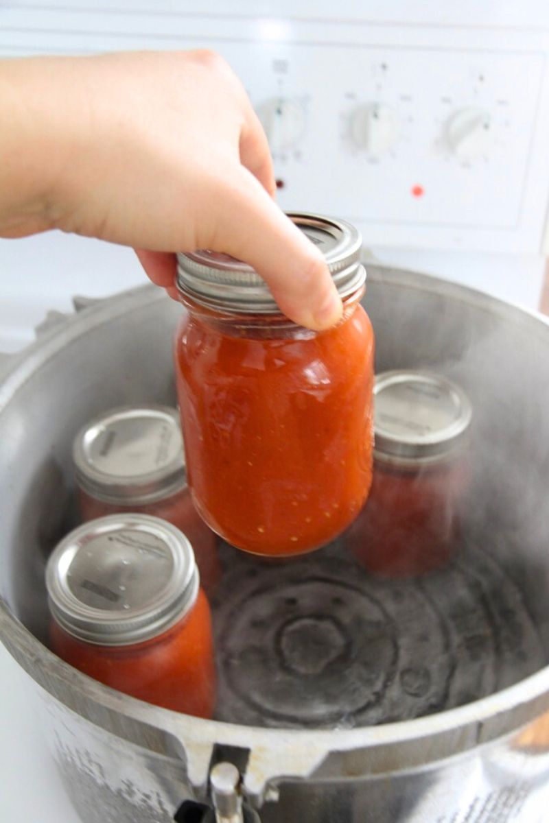 Setting filled jars of tomato sauce in a hot pressure canner.