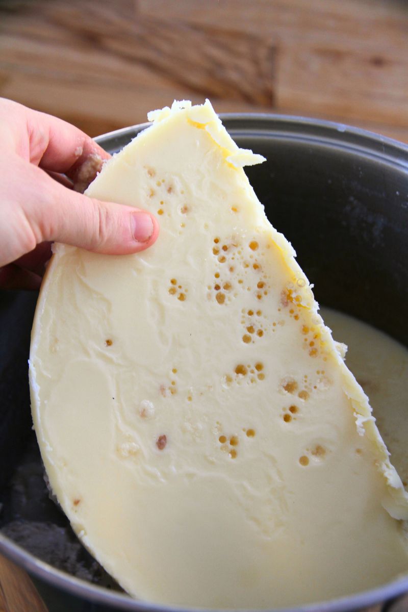 Lifting a light yellow layer of hardened beef fat off of cold broth, so I can preserve it in a pressure canner.