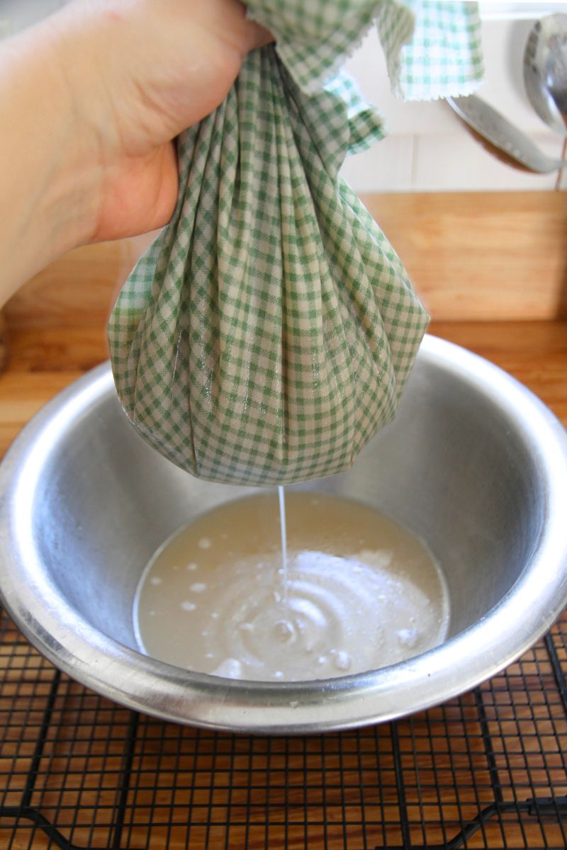 Straining warm broth through a cotton cloth to catch bits of bone and cartilage.