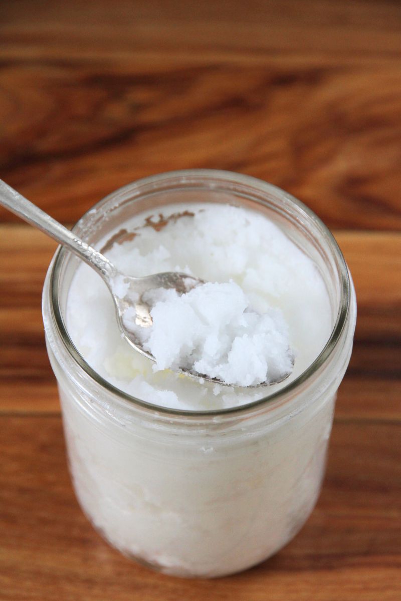 A spoon stuck in a jar of white coconut oil that will be used for seasoning cast iron.
