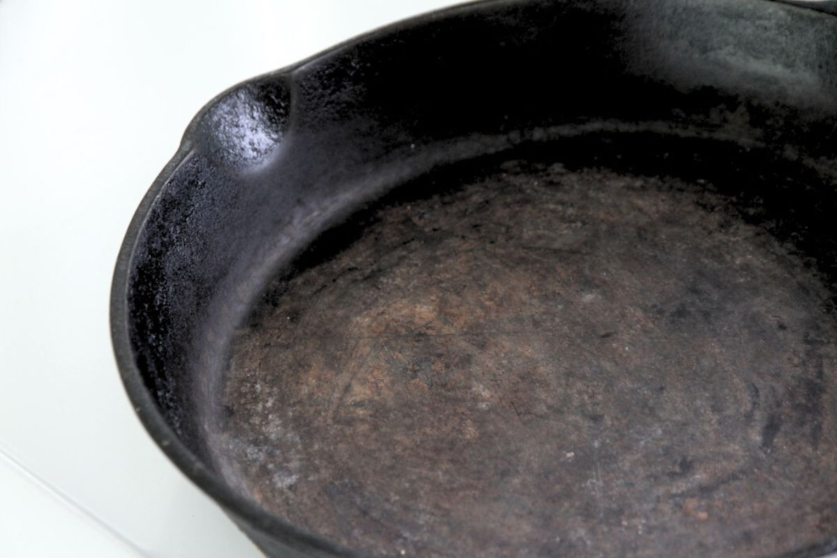 A cast iron pan with some orange iron oxide on the cooking surface.