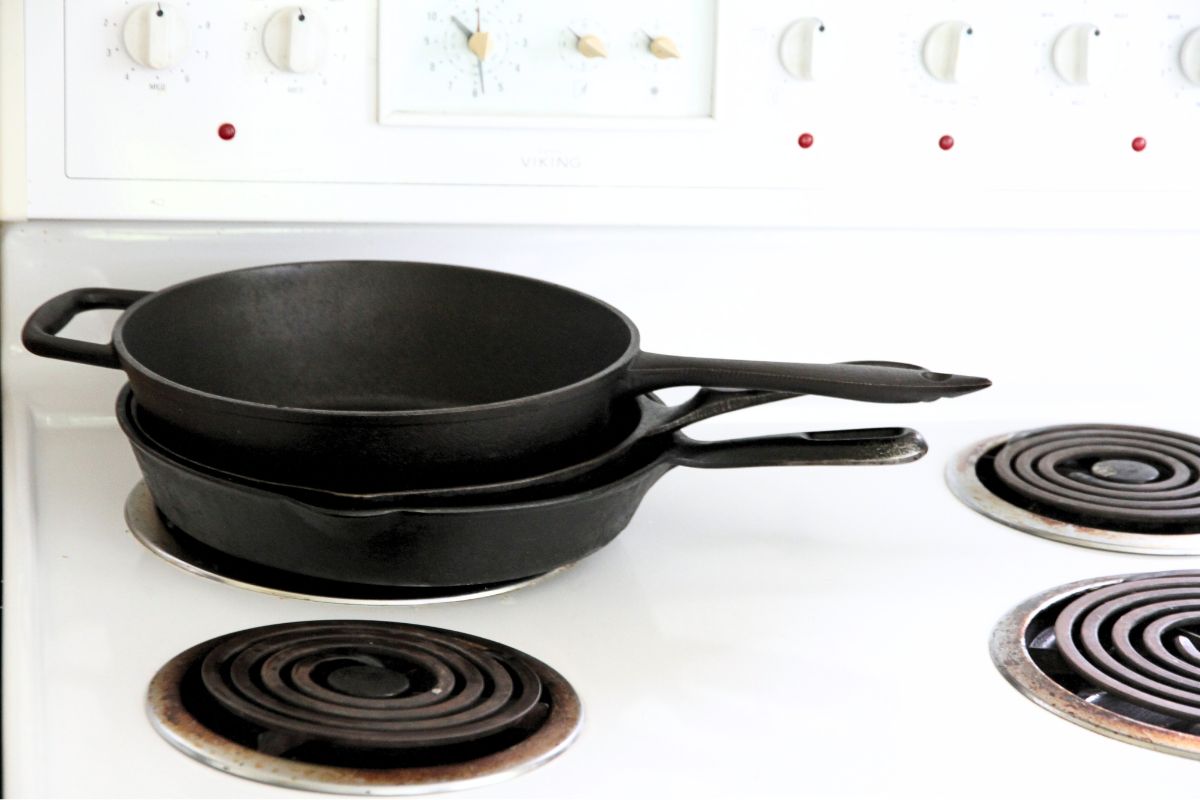 A stack of cast iron skillets on a white kitchen stove.