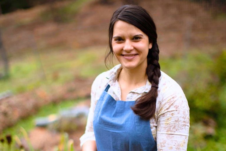 A woman standing in a garden in her blue apron