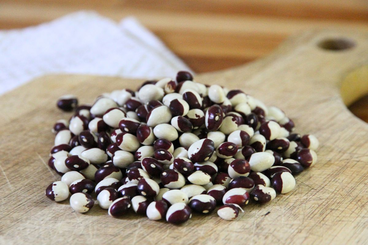 A pile of dried shelling beans on a wooden kitchen cutting board, ready for cooking.