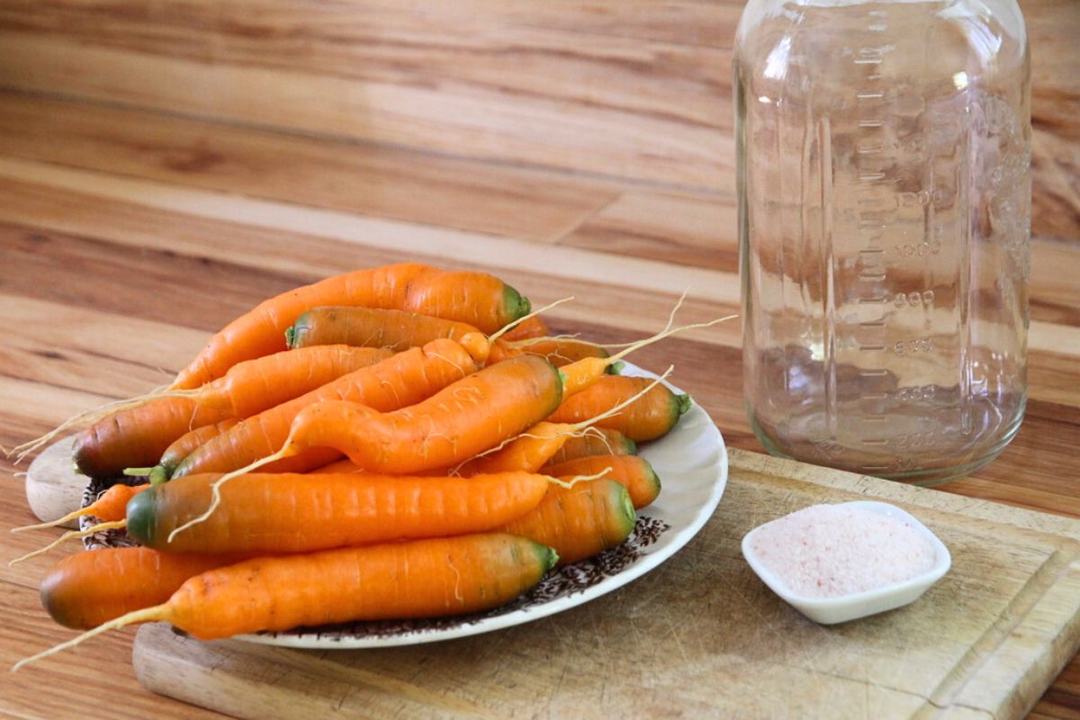 A plate full of fresh garden carrots, with salt and a mason jar nearby.
