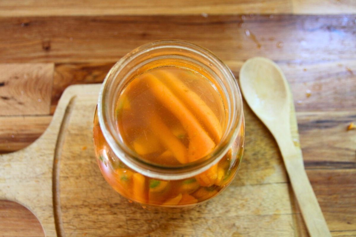 A glass jar filled with salt brine and carrot sticks.