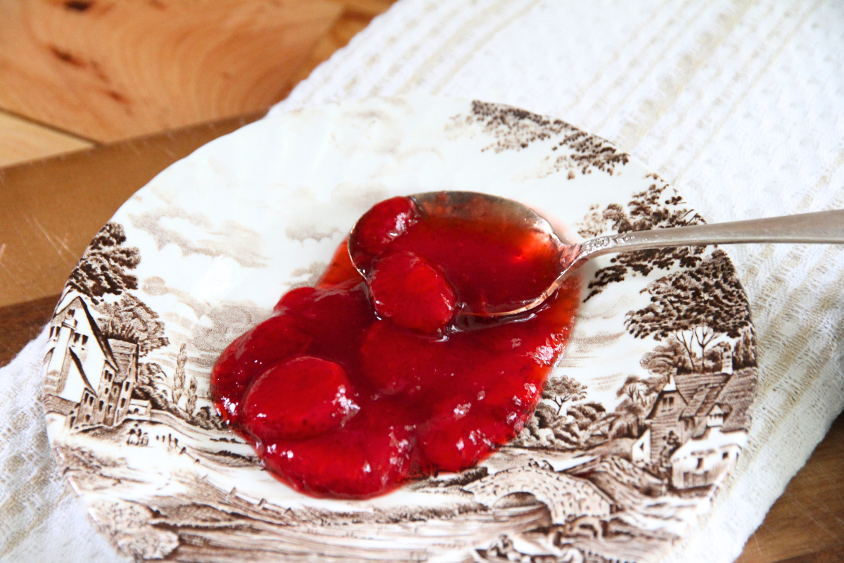 Strawberry sauce spooned on a saucer, to show the chunks of strawberries in the red sauce. 