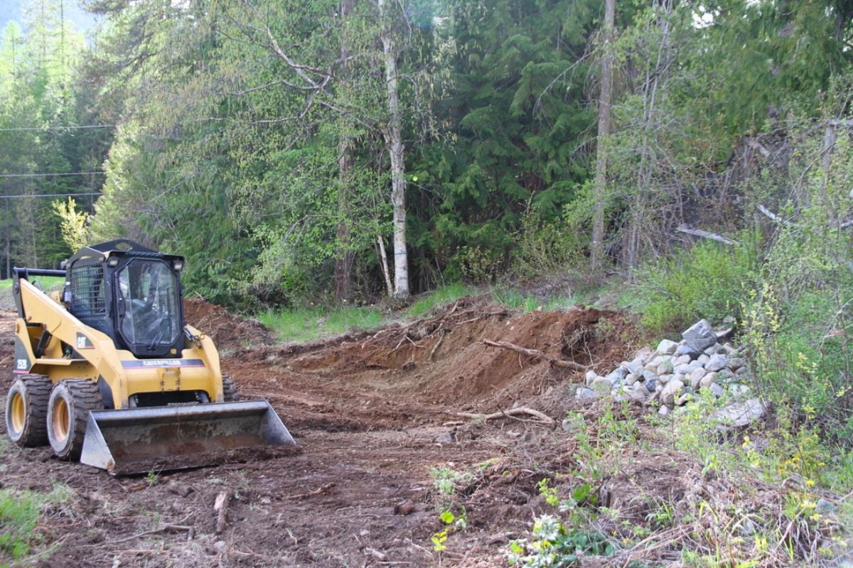 A Bobcat scraping away earth at the base of a hillside where the root cellar will be.