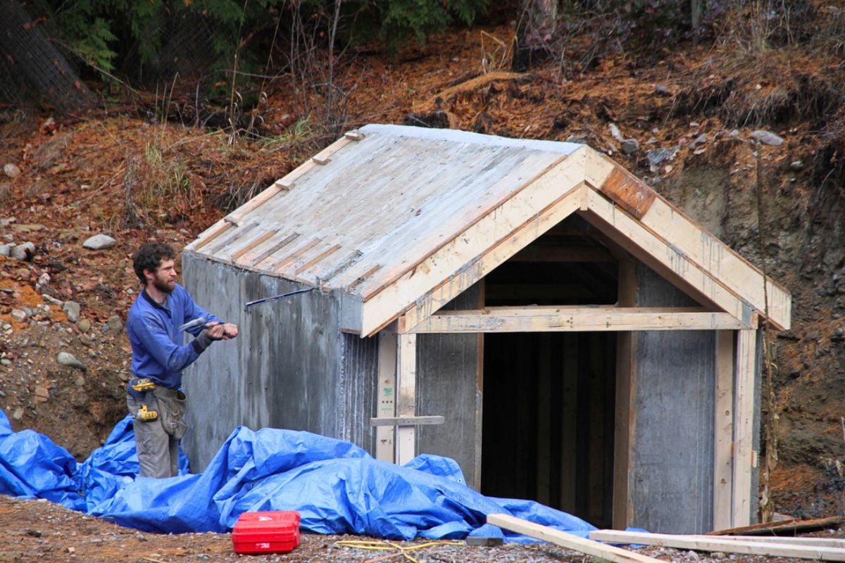 My man hammering a crowbar between the concrete forms and hardened concrete of the root cellar. 