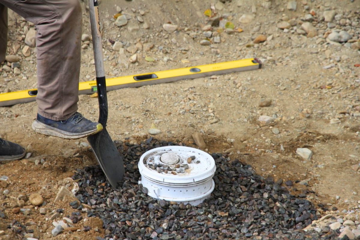 A 5 gallon bucket with a lid being buried on the floor of the root cellar for a sump pit. 