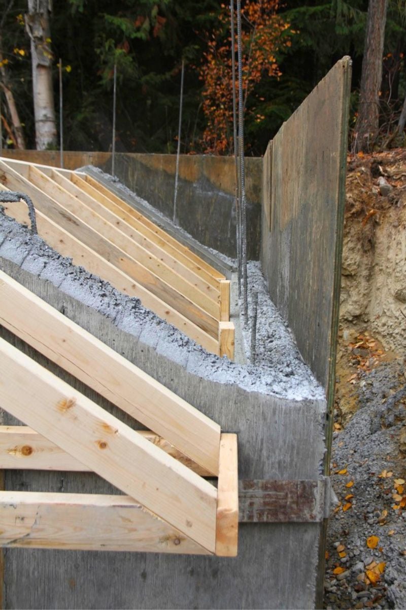 Concrete walls of a root cellar with rebar sticking up beyond the top of the wall. 