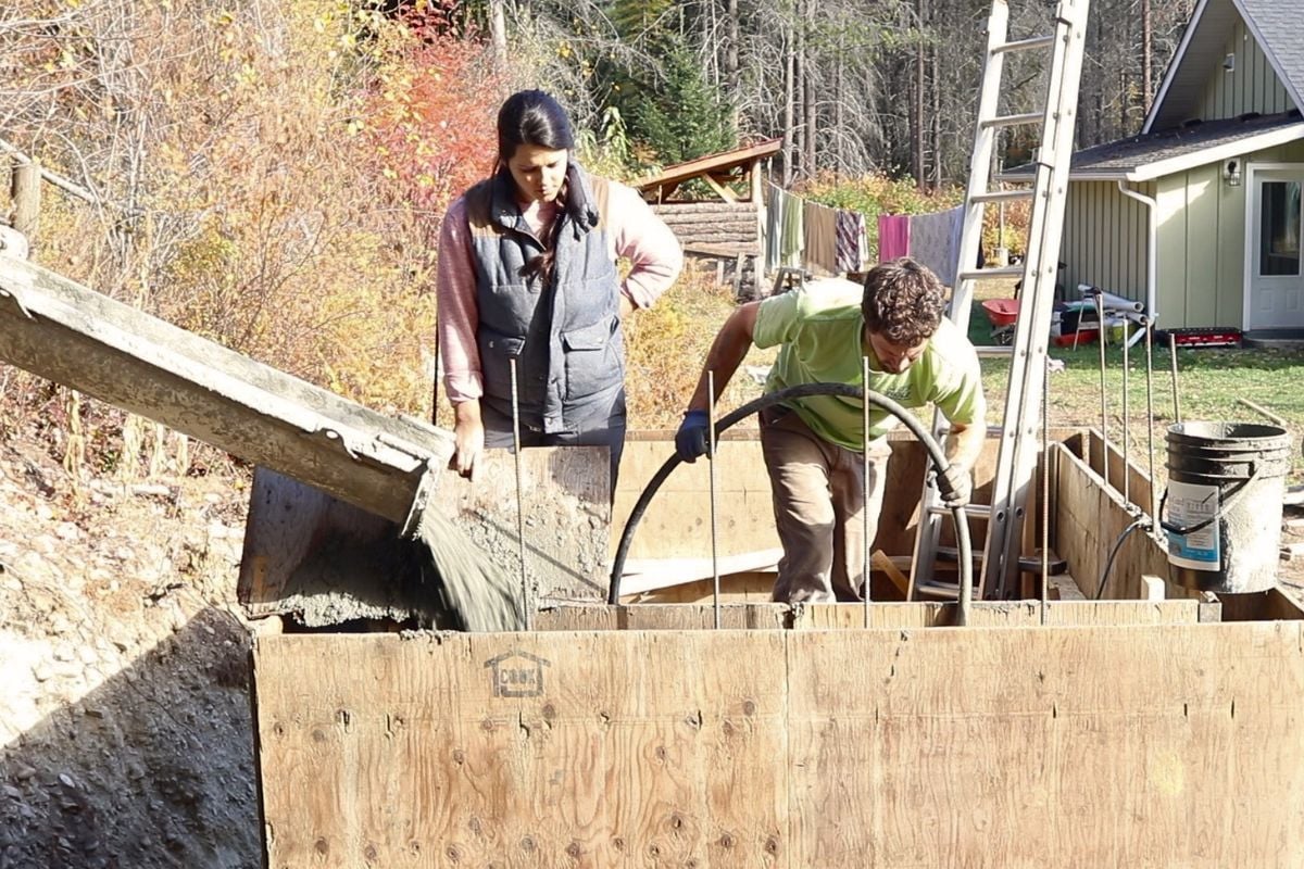 Pouring concrete from a chute into the wall forms, while running a pencil vibrator to get air bubbles out. 