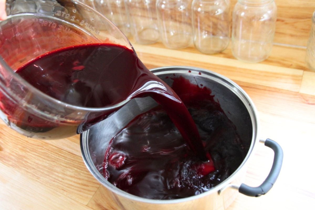 Pouring fresh blackberry juice into a large stockpot for heating.