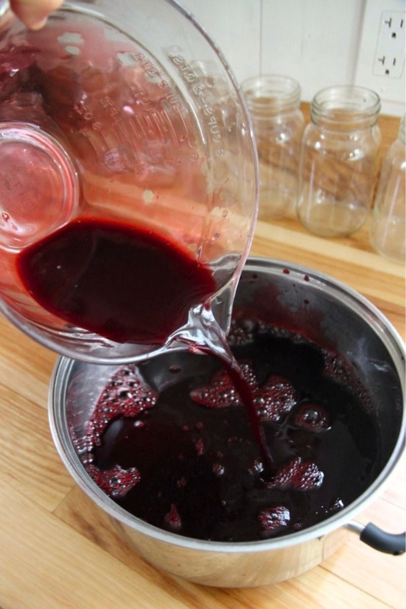 Fresh blackberry juice being poured in a stock pot for warming. 