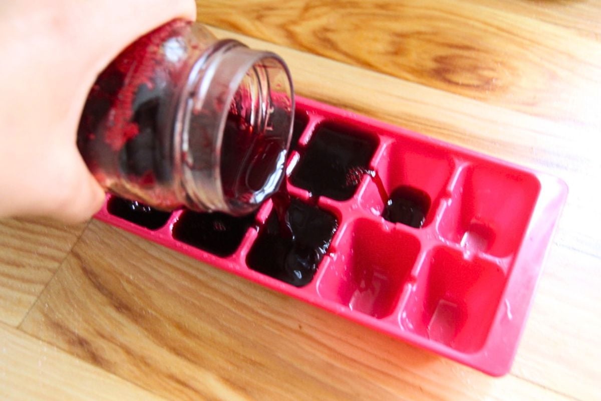 Pouring blackberry juice into ice cube molds, to freeze for smoothies.