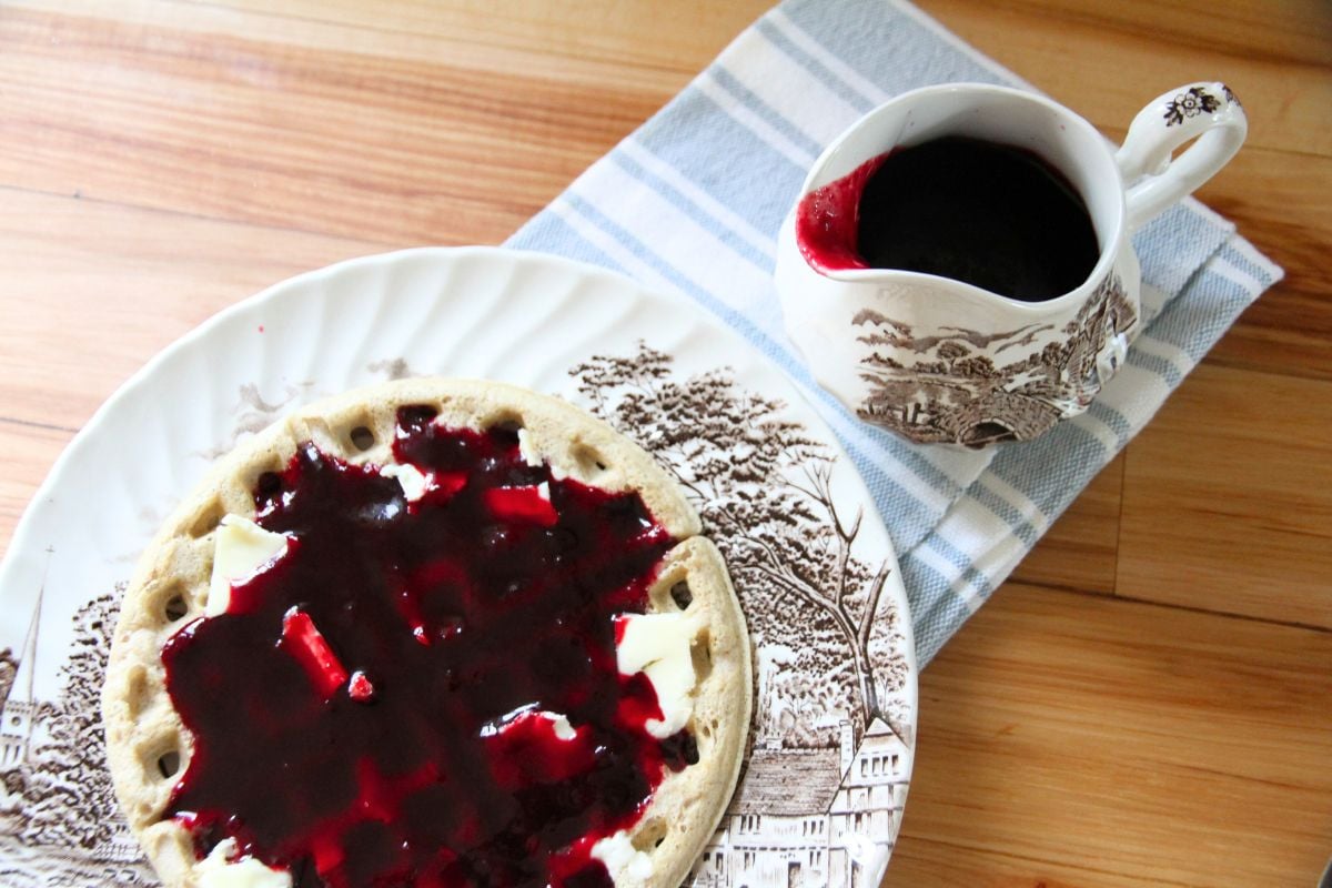 Blackberry syrup poured over a fresh breakfast waffle.