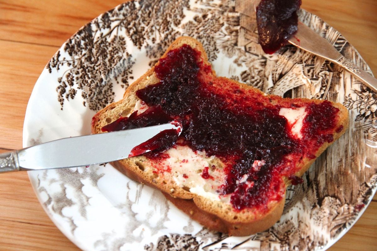 Spreading honey sweetened blackberry jelly on breakfast toast.