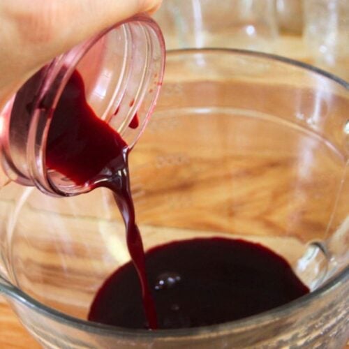 Pouring blackberry juice into a measure bowl.