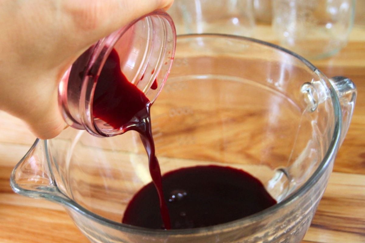 Pouring blackberry juice into a measure bowl.