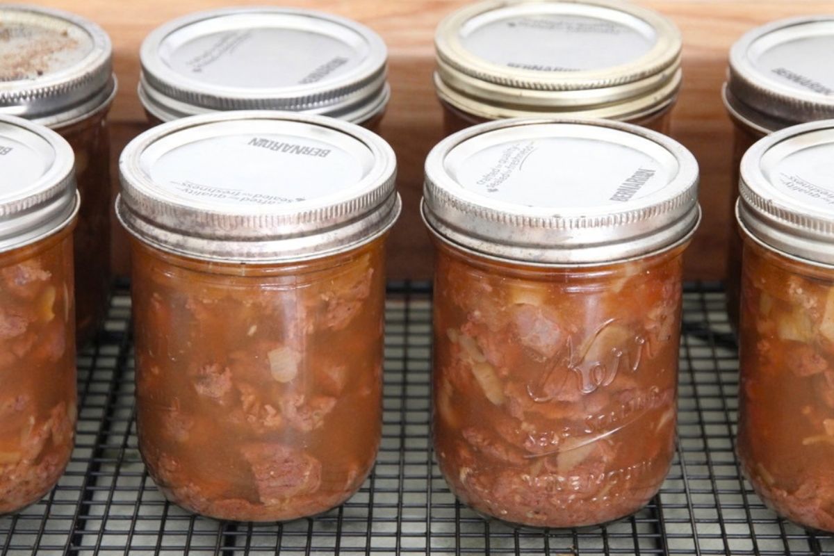 Canned jars of bear meat, cooking on a kitchen counter.