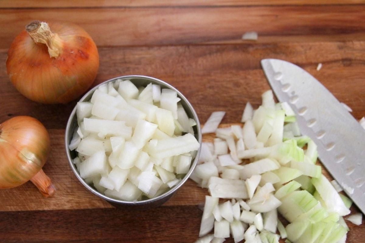 Chopped onions on a wood cutting board, ready for searing with bear meat.